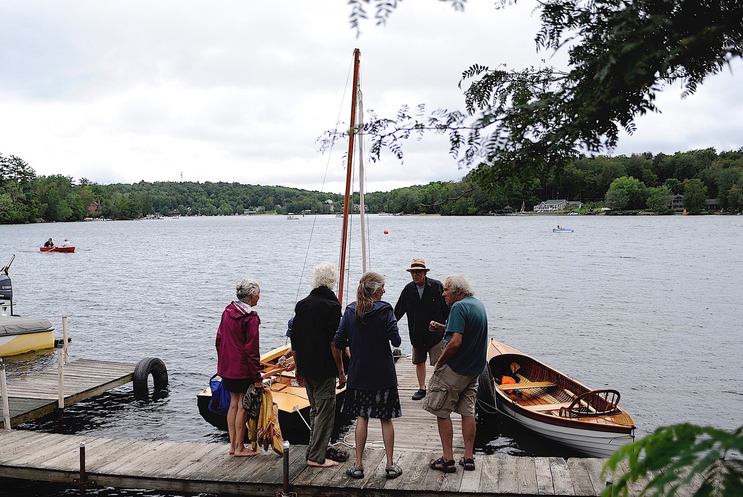 Dockside chat. Members of the Beechwoods Yacht Club and friends gather at the Fat Lady Café dock, as Joe and Elise Freda cross the lake in their newest acquisition, a restored 1938 Penn Yan Cartopper.